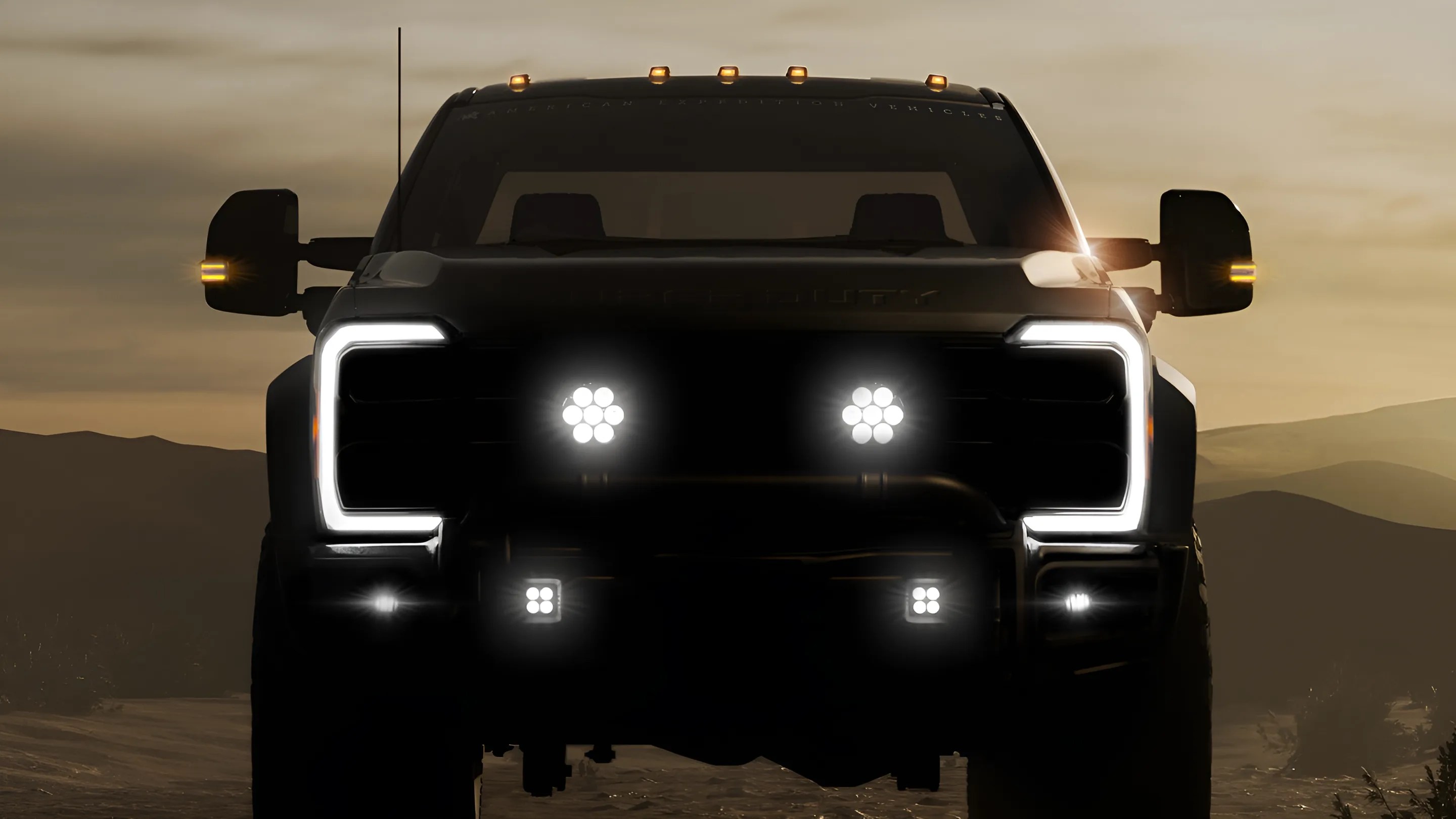 Front view of a black pickup truck with LED headlights and amber side mirror lights at dusk.