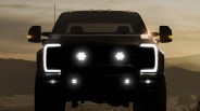 Front view of a black pickup truck with LED headlights and amber side mirror lights at dusk.