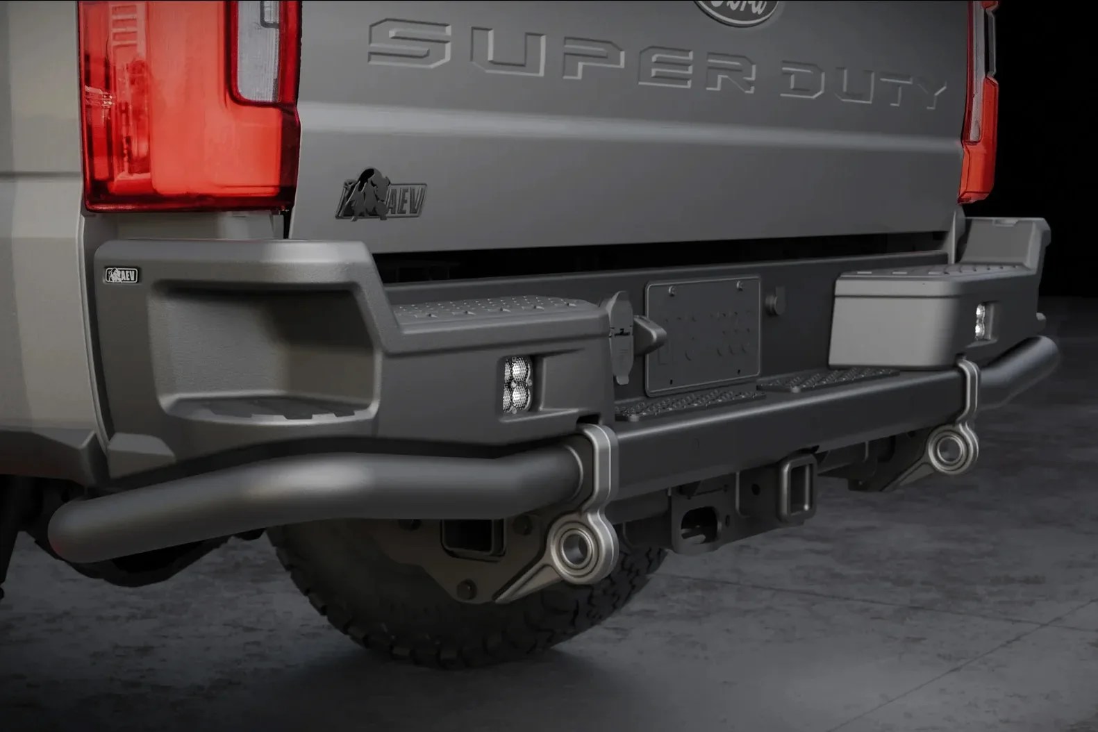 Rear view of a gray Super Duty truck with a black AEV branded heavy-duty bumper and integrated step lights.