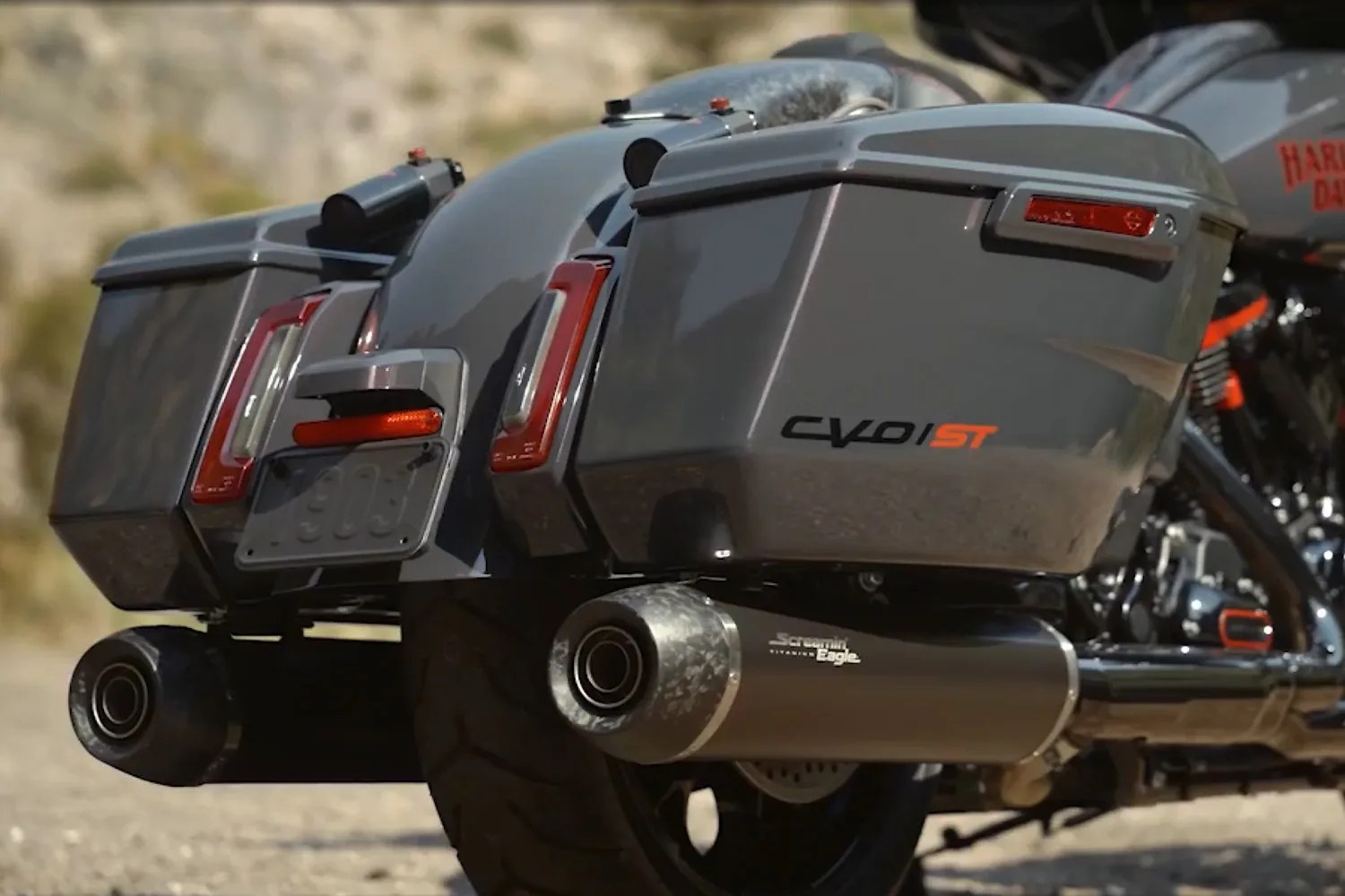 Close-up of a gray Harley-Davidson CVO ST motorcycle rear with dual Screamin' Eagle exhaust pipes and saddlebags.
