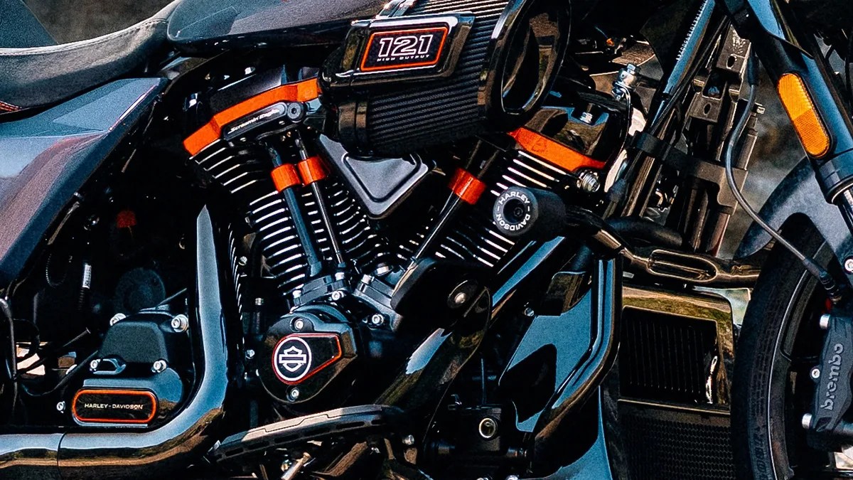 Close-up of a black Harley-Davidson motorcycle engine with orange accents and "121 High Output" air filter.
