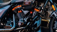 Close-up of a black Harley-Davidson motorcycle engine with orange accents and "121 High Output" air filter.
