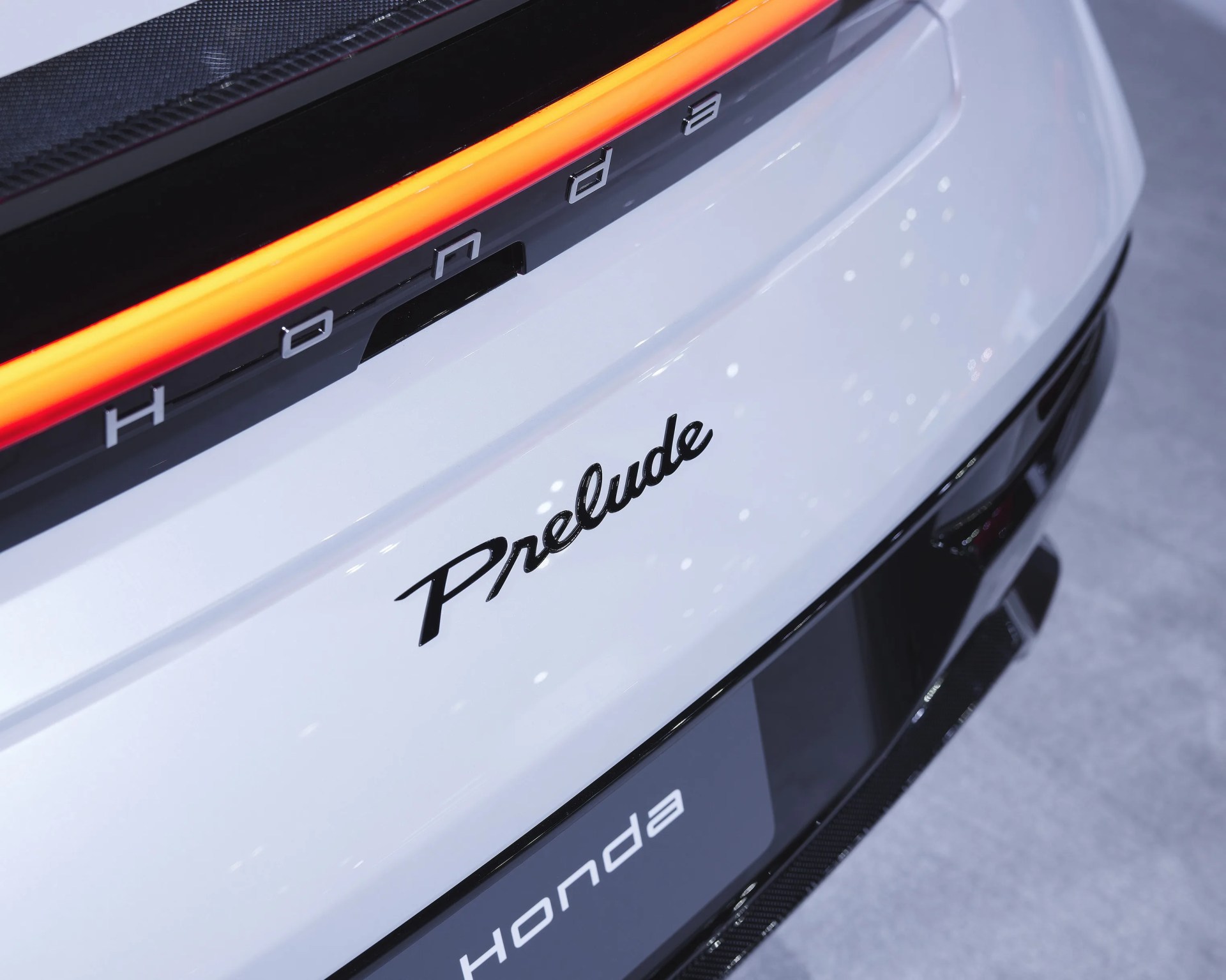 Rear view of a white Honda Prelude with black "Prelude" script and illuminated red tail light strip.