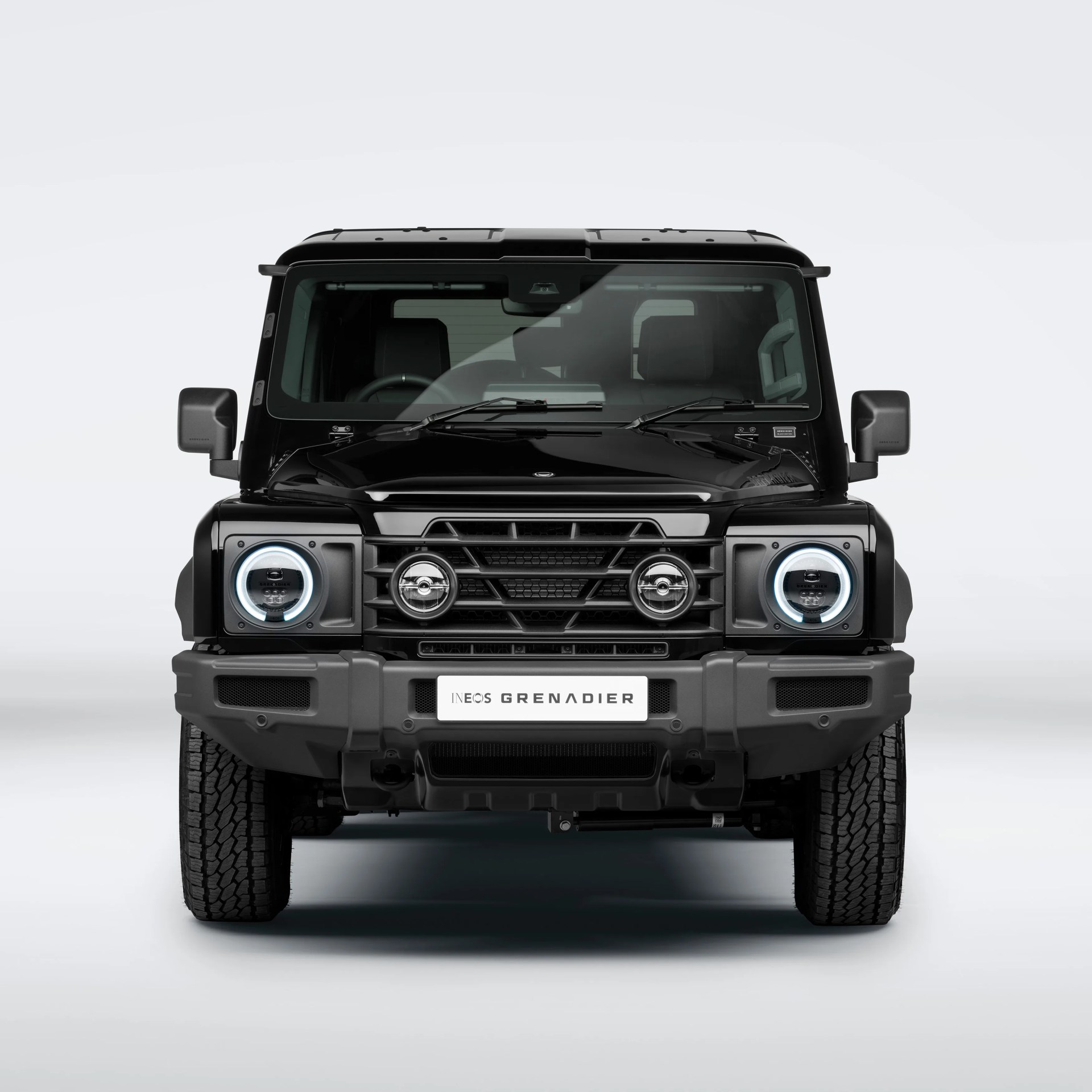 Front view of a black INEOS Grenadier SUV with round LED headlights and a rugged grille.