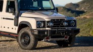 Beige off-road SUV front with black grille, round headlights, snorkel, and rugged BFGoodrich All-Terrain tires on gravel.