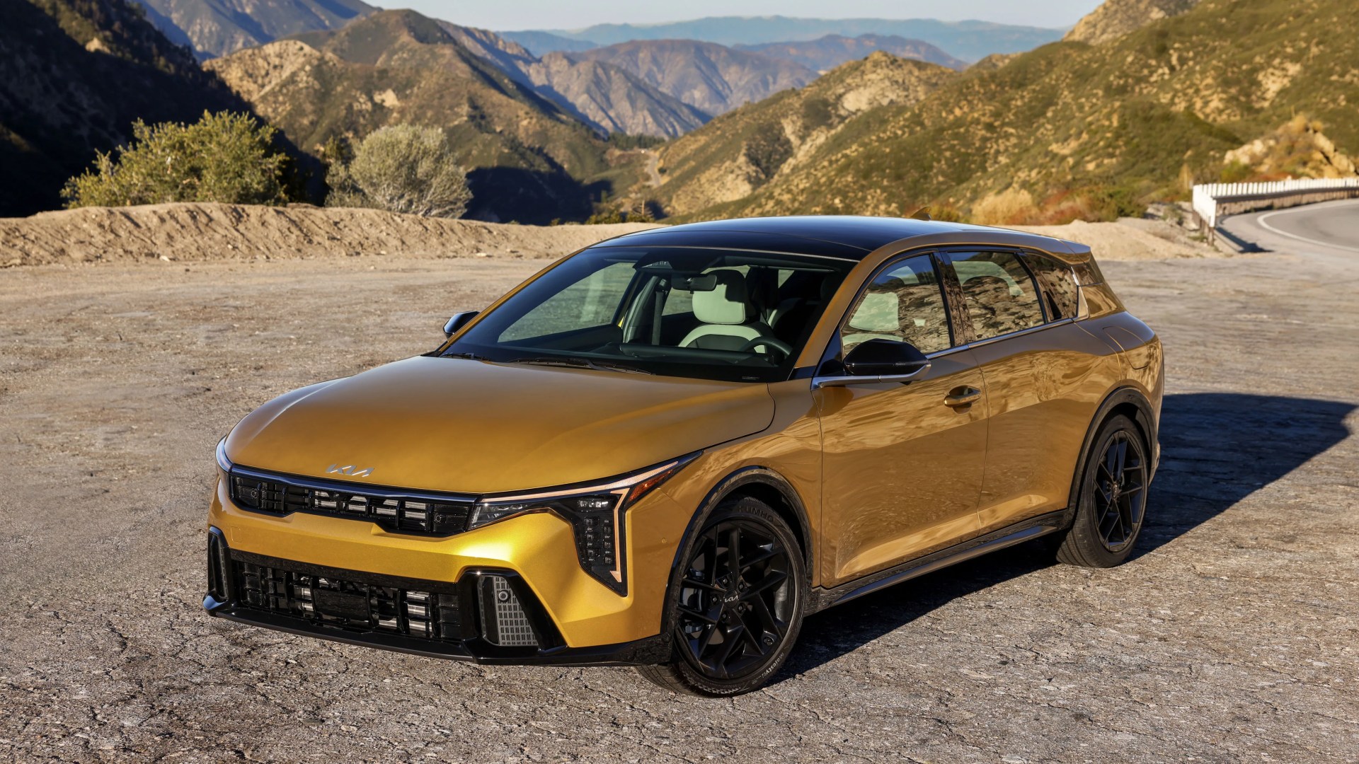 Gold Kia station wagon with black roof and black wheels parked on a mountain road.