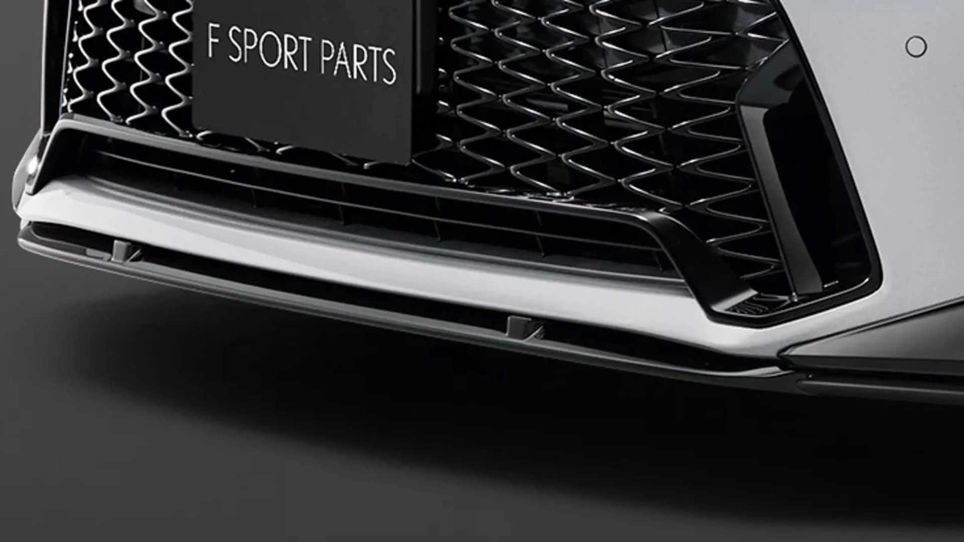 Close-up of a car front grille with a black mesh pattern and a white lower lip spoiler labeled "F SPORT PARTS.