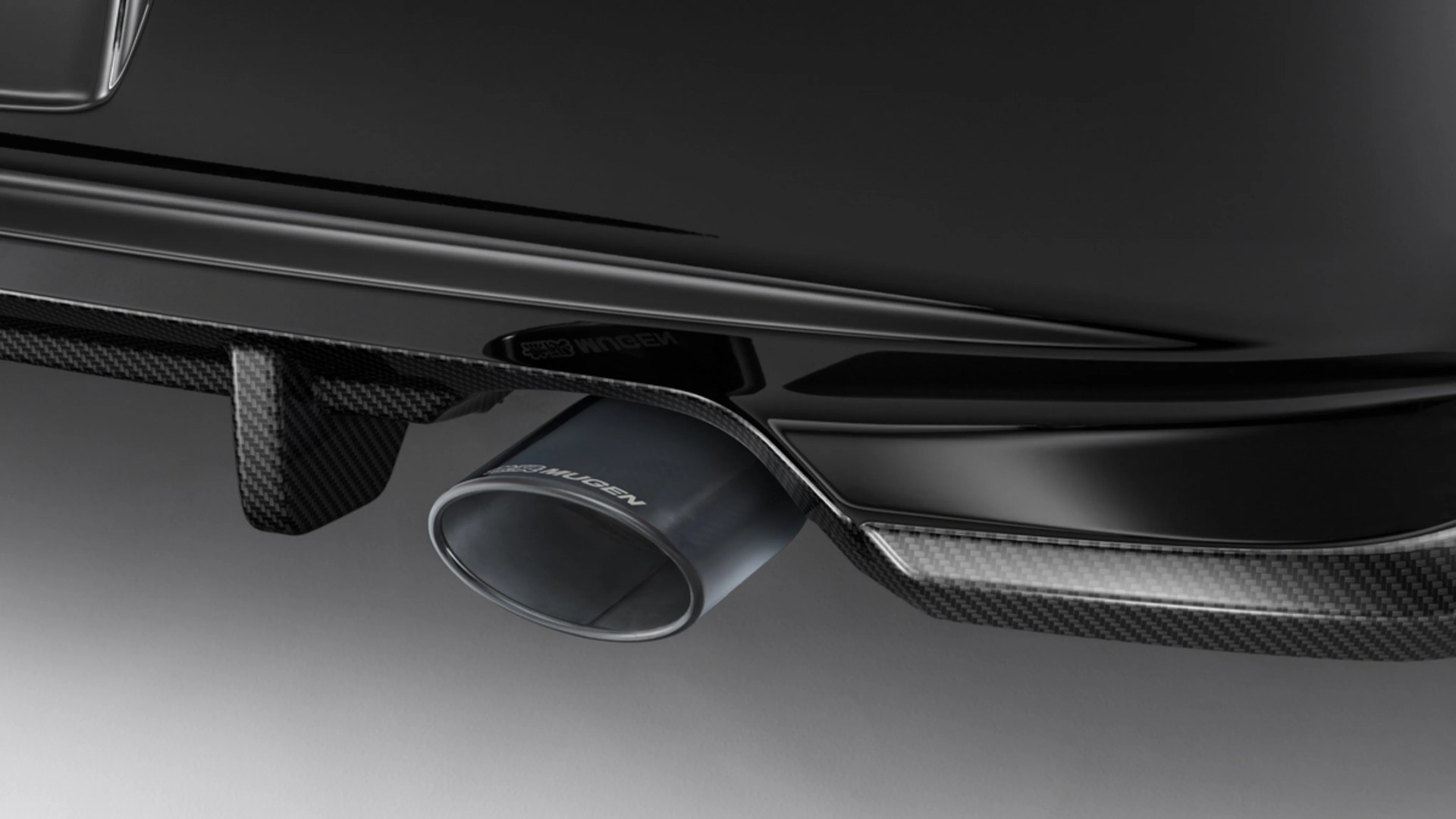 Glossy black car rear diffuser with carbon fiber accents and a large Mugen-branded exhaust tip.