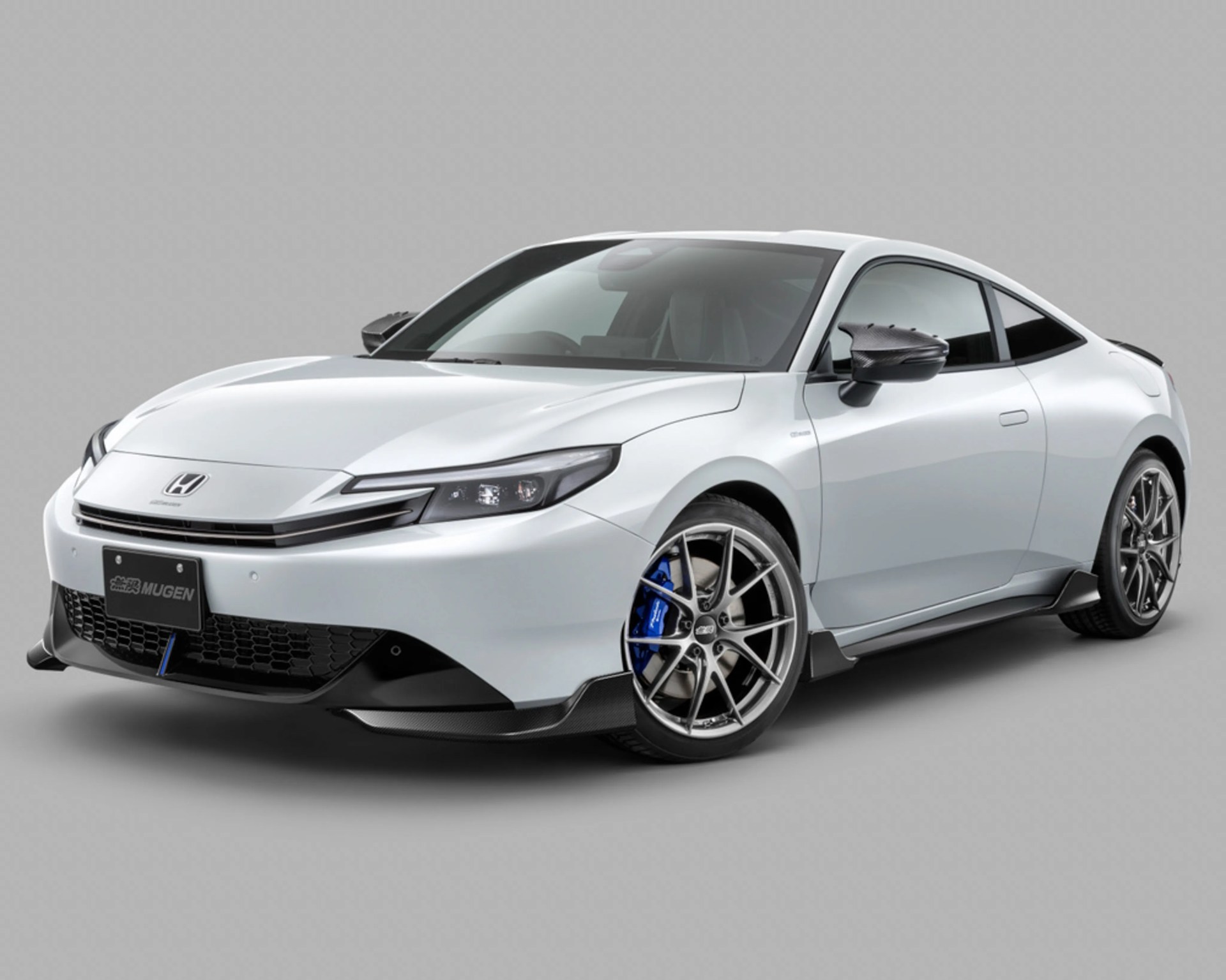 White Honda sports coupe with carbon fiber side mirrors and blue brake calipers on gray background.