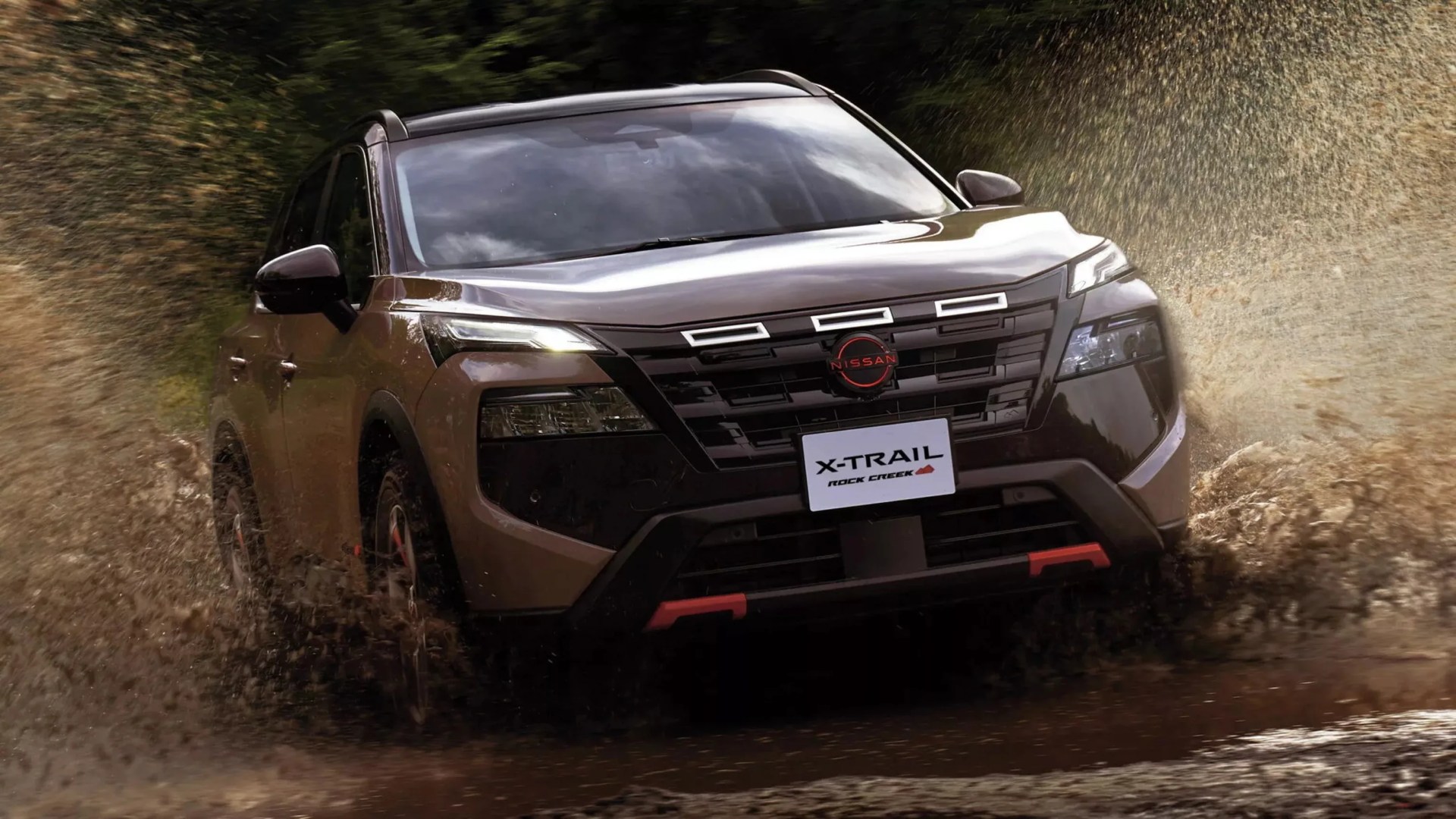 Brown Nissan X-Trail Rock Creek SUV splashing through muddy water, front view.