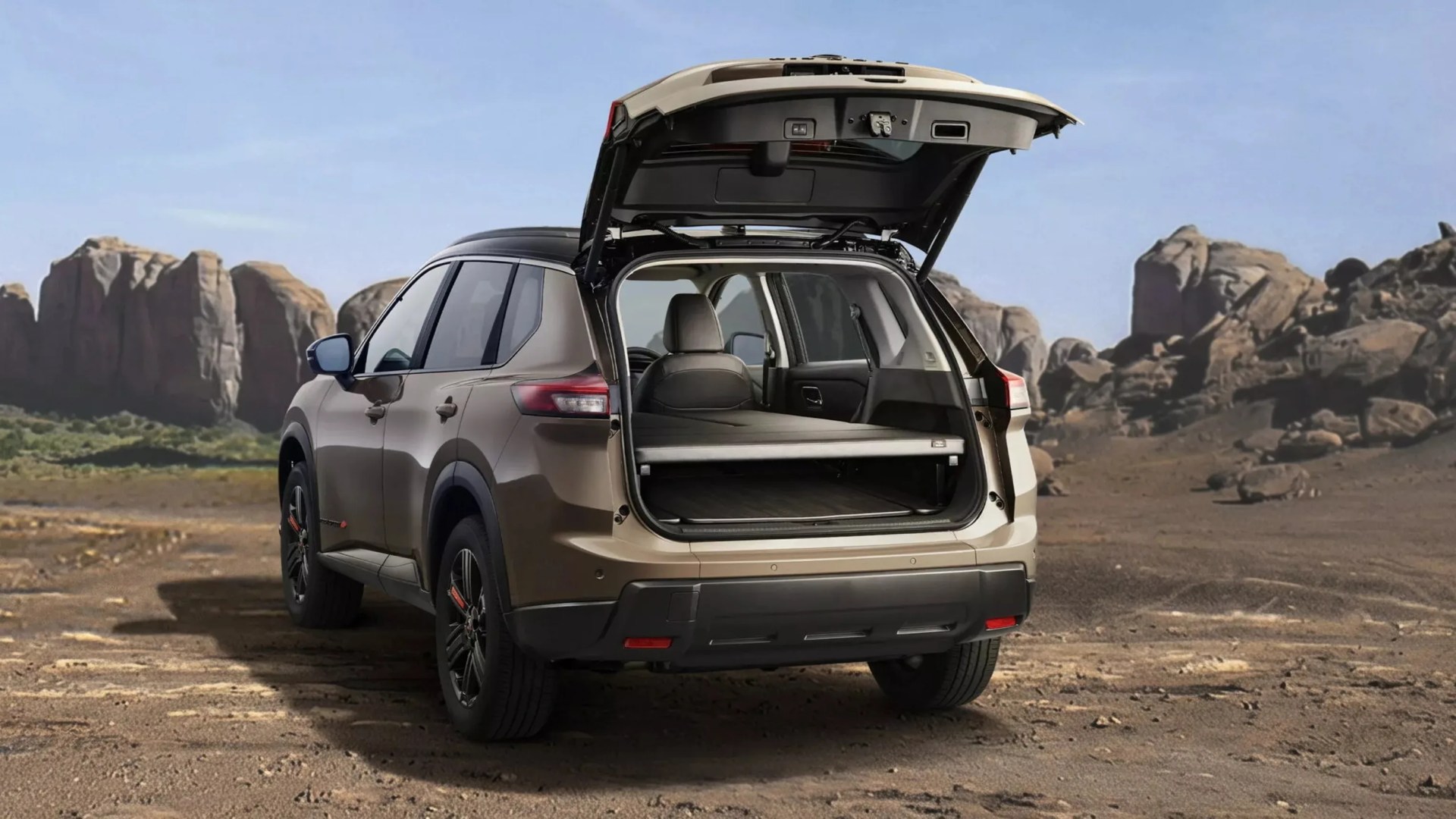 Brown SUV with open rear hatch showing cargo area, parked on rocky terrain with large rock formations in background.