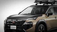 Front side view of a beige and black Nissan X-Trail Rock Creek edition SUV with roof rack and black fender flares.