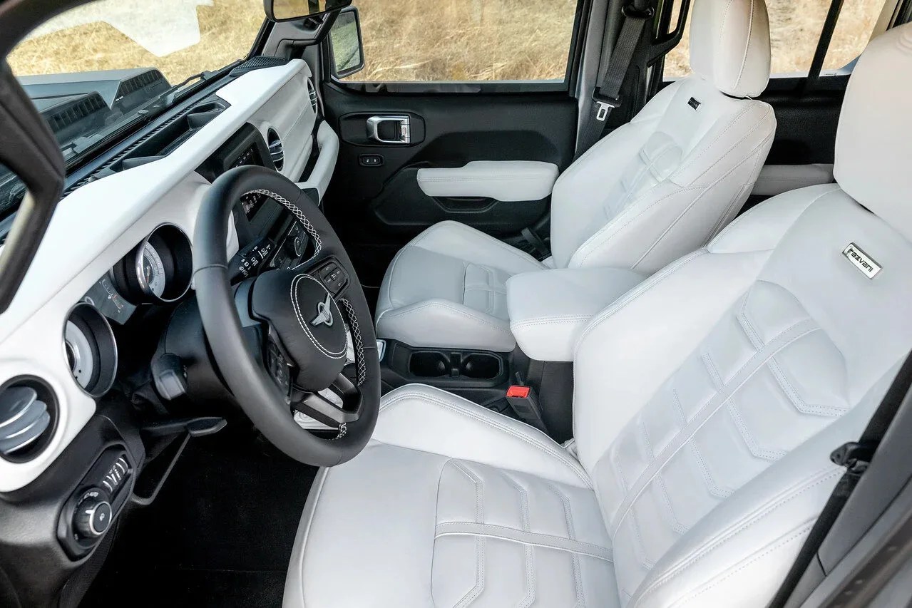 White leather front seats with "Raven" branding inside a vehicle with a black and white dashboard and steering wheel.