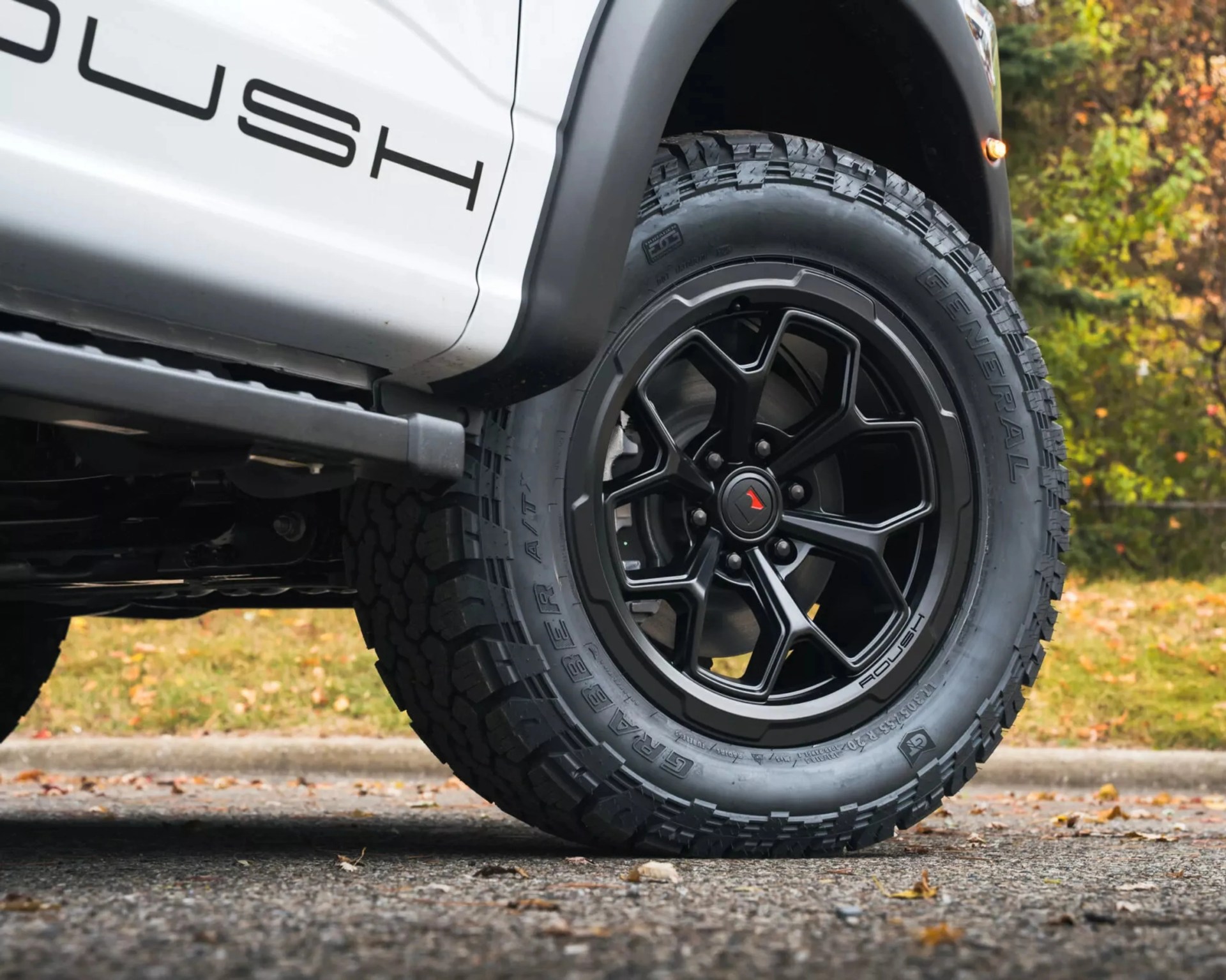 Black multi-spoke Rough Country wheel with General Grabber ATX tire on a white vehicle.