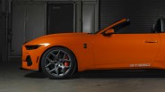 Orange convertible sports car with GT350 decal and gray alloy wheels in a dimly lit garage.