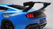 Blue Shelby Racing car rear with large black spoiler and red arrow-shaped taillights.