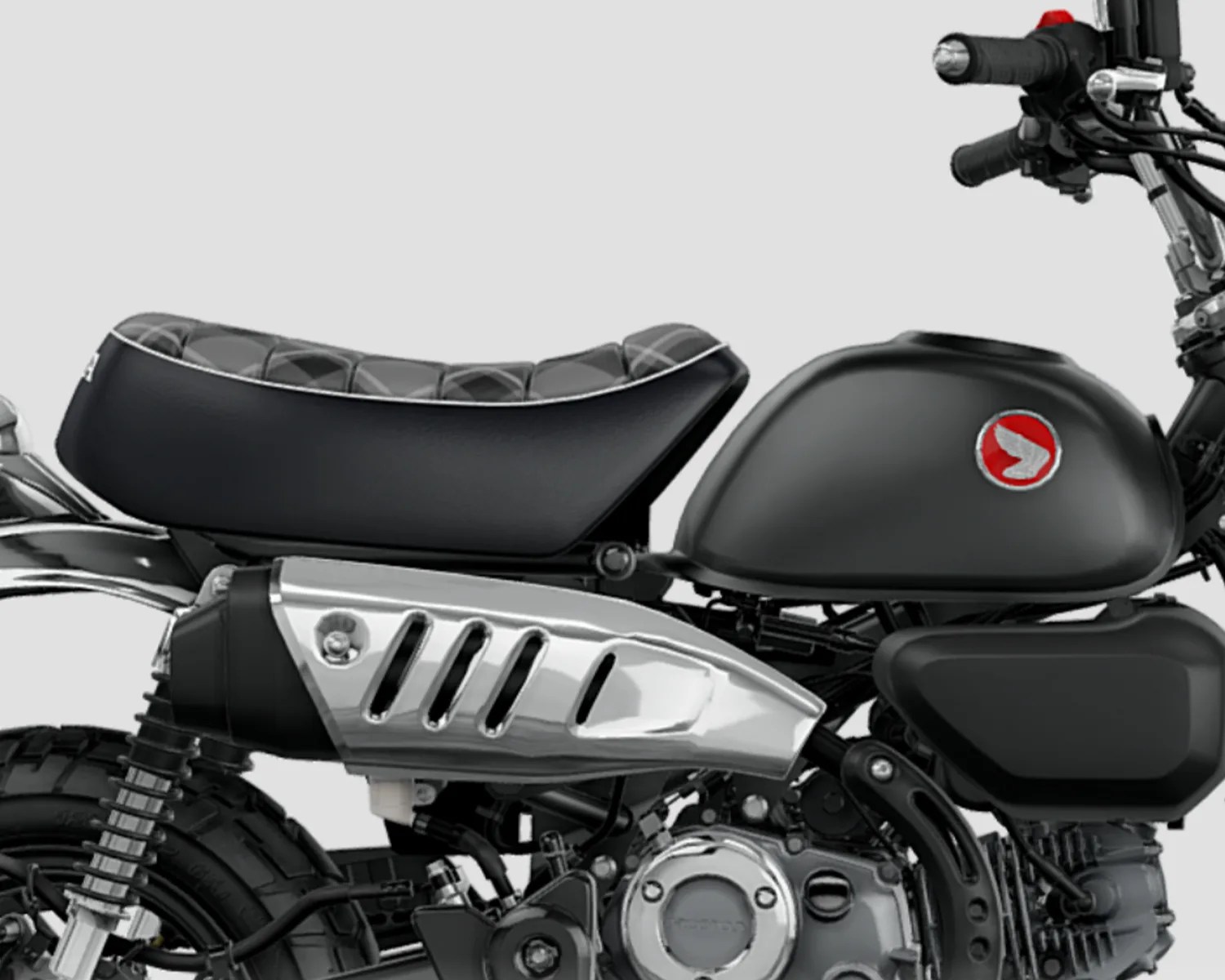 Close-up of a black motorcycle seat and fuel tank with a red and white logo on the tank.