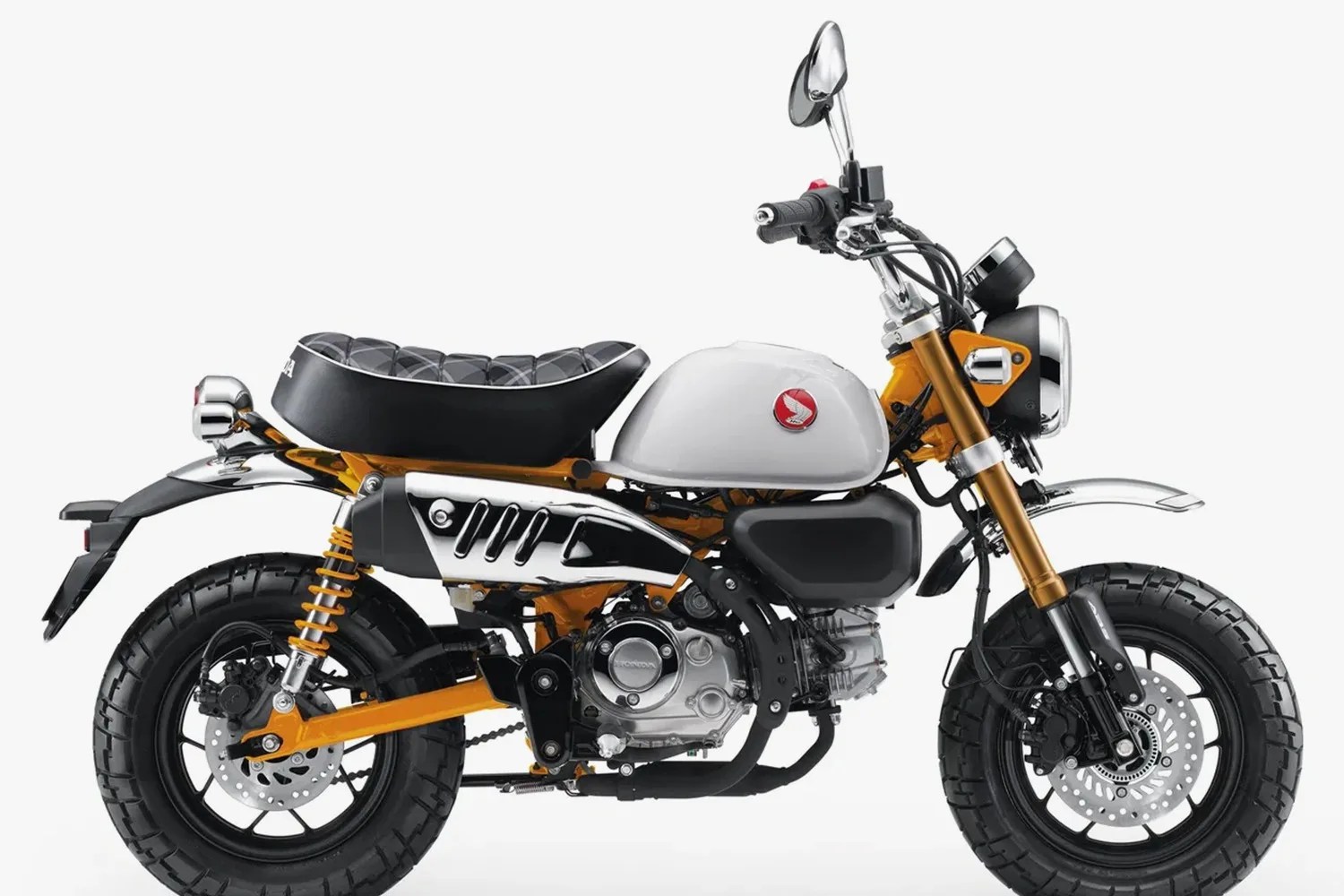 White and orange Honda mini motorcycle with black seat and chunky tires on a white background.