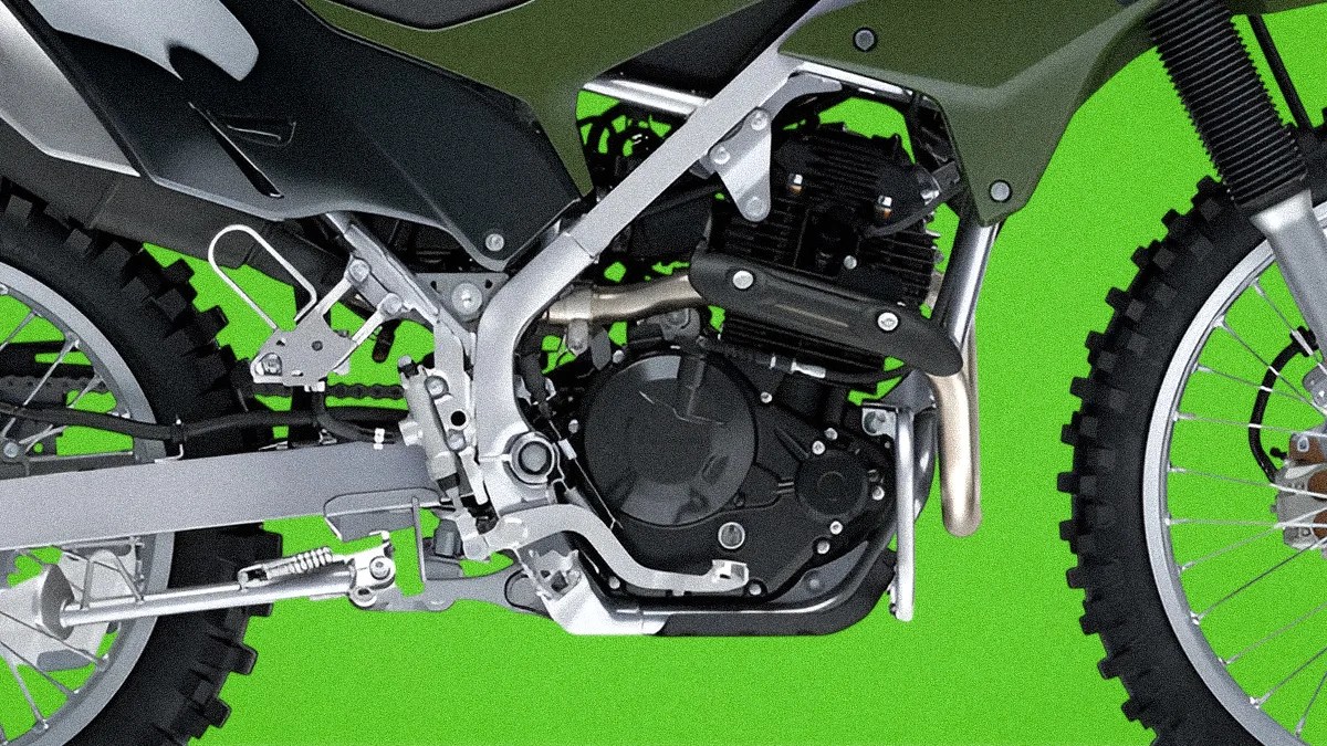 Close-up of a silver and black motorcycle engine and frame with knobby tires against a green background.