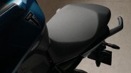 Close-up of a black motorcycle seat with a blue Triumph logo on the adjacent body panel.