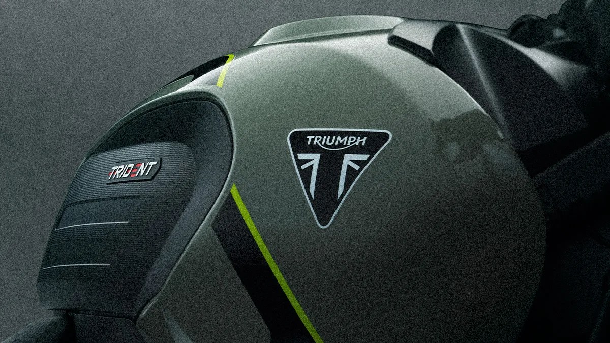 Close-up of a matte green motorcycle fuel tank with black and yellow stripes, featuring Triumph and Trident logos.