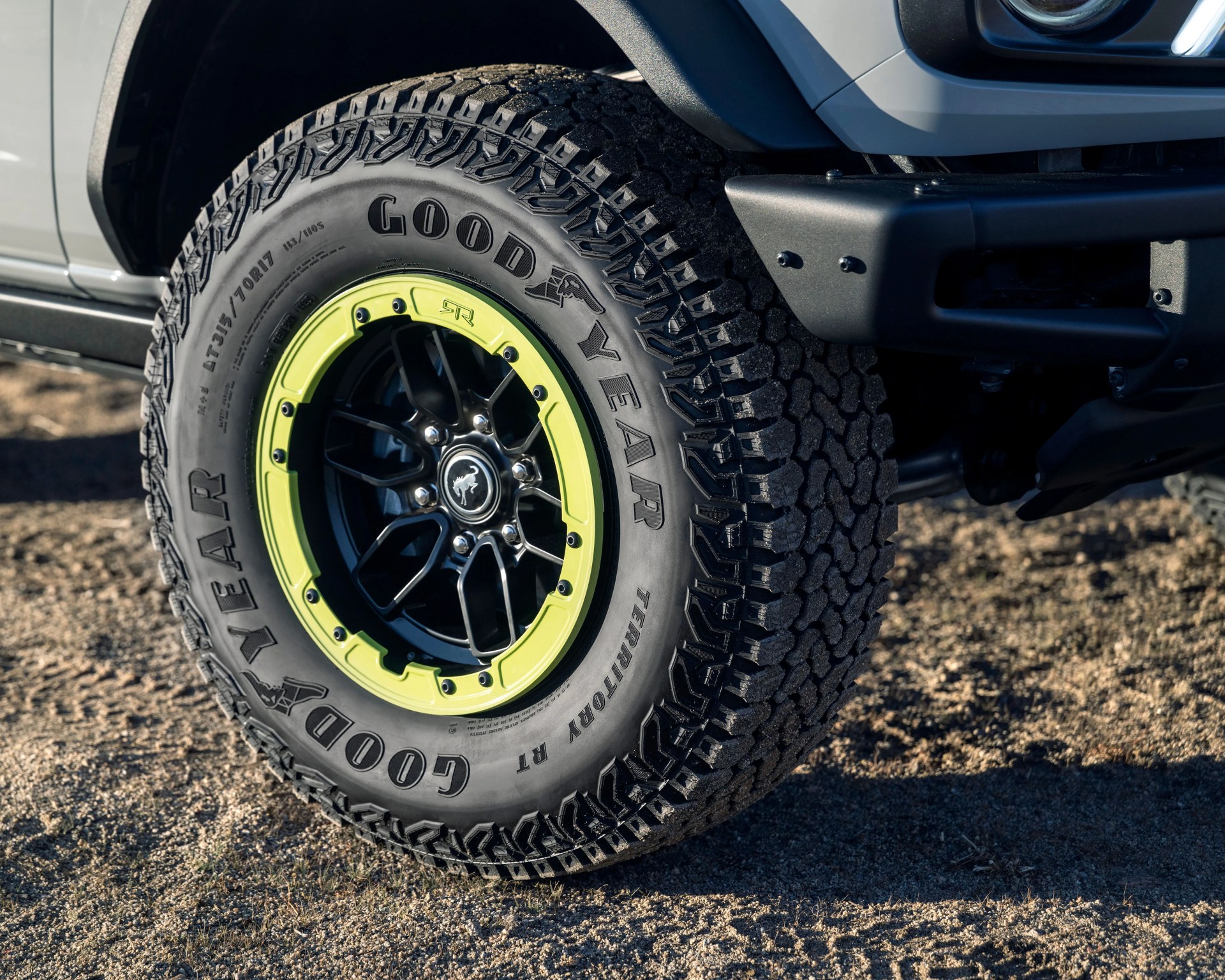 Goodyear off-road tire with aggressive tread mounted on black and neon green alloy wheel on a vehicle.