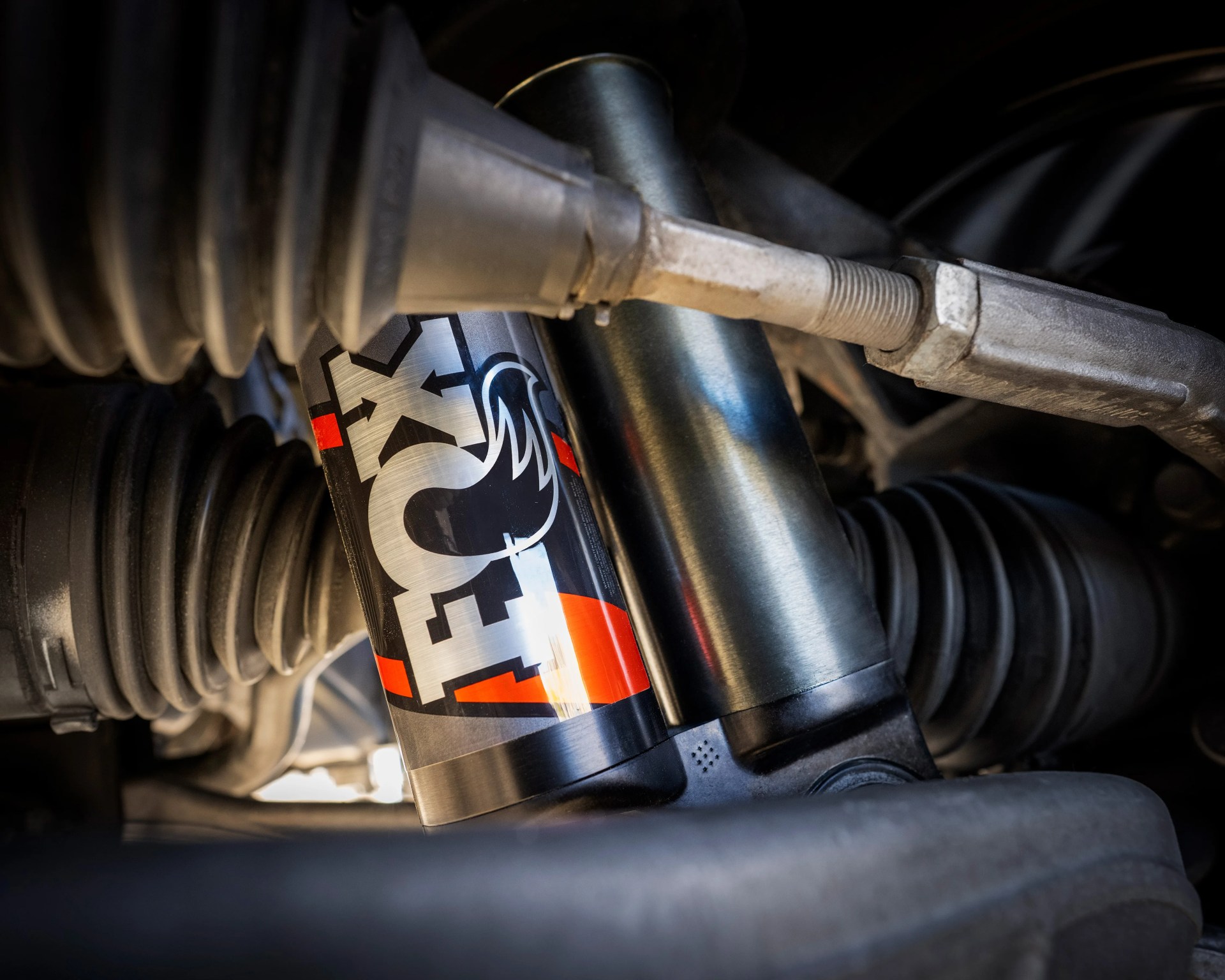 Close-up of a black and silver FOX shock absorber with red accents installed in a vehicle suspension system.