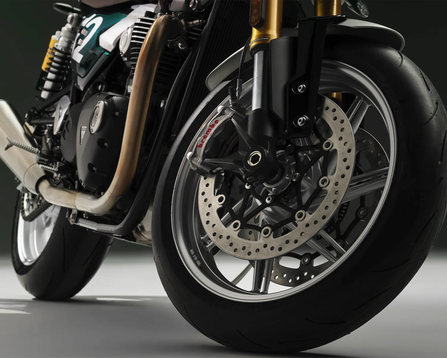 Close-up of a motorcycle front wheel with Brembo brake caliper, disc brake, and black tire.