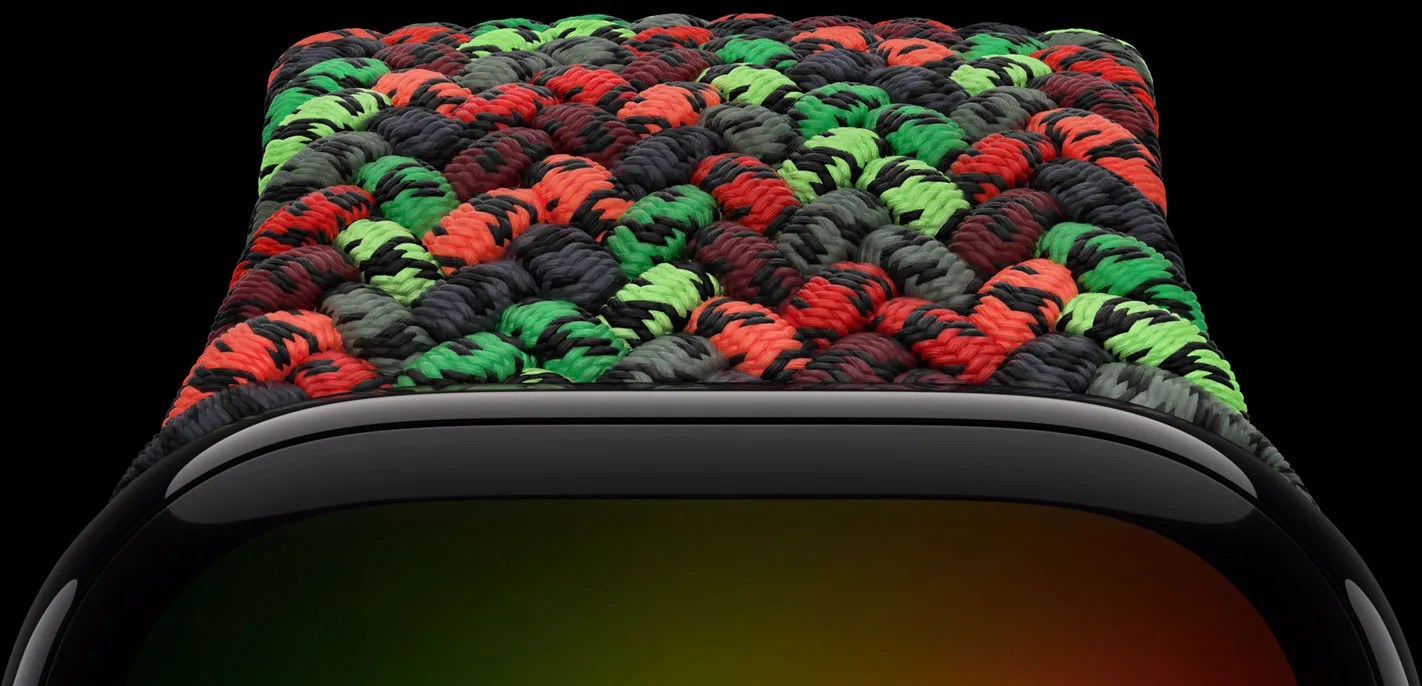 Close-up of a black smartwatch with a braided nylon band in red, green, and black colors.