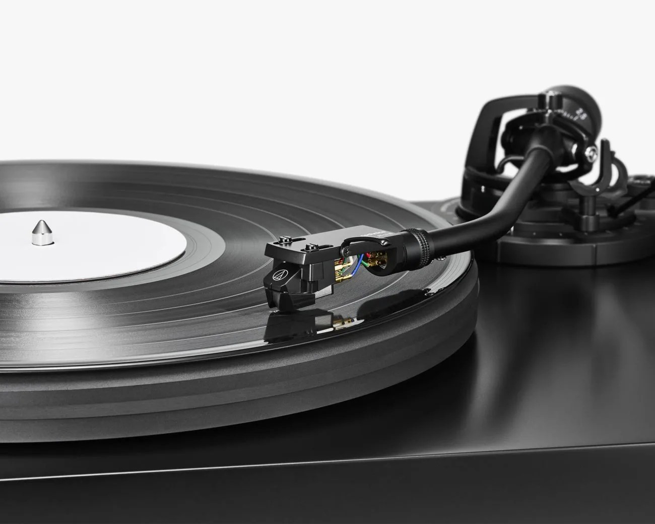 Close-up of a black turntable with a vinyl record and a tonearm positioned over the record.
