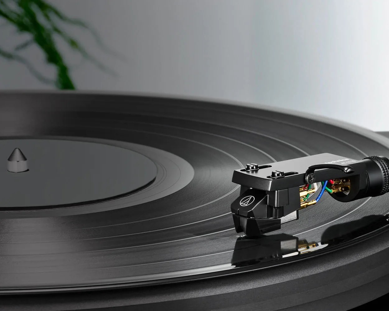 Close-up of a black vinyl record playing on a turntable with a black tonearm and cartridge.
