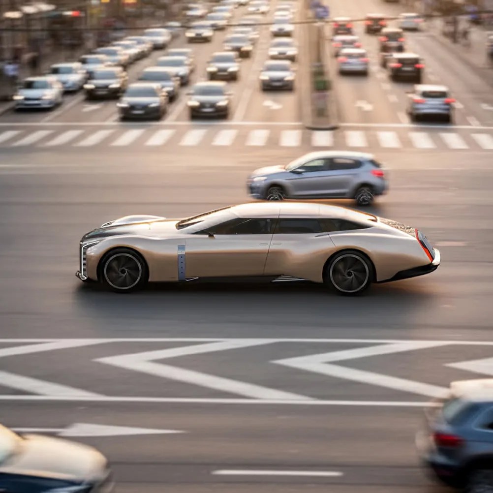 Sleek, metallic silver futuristic luxury car driving on a busy city street with blurred background traffic.