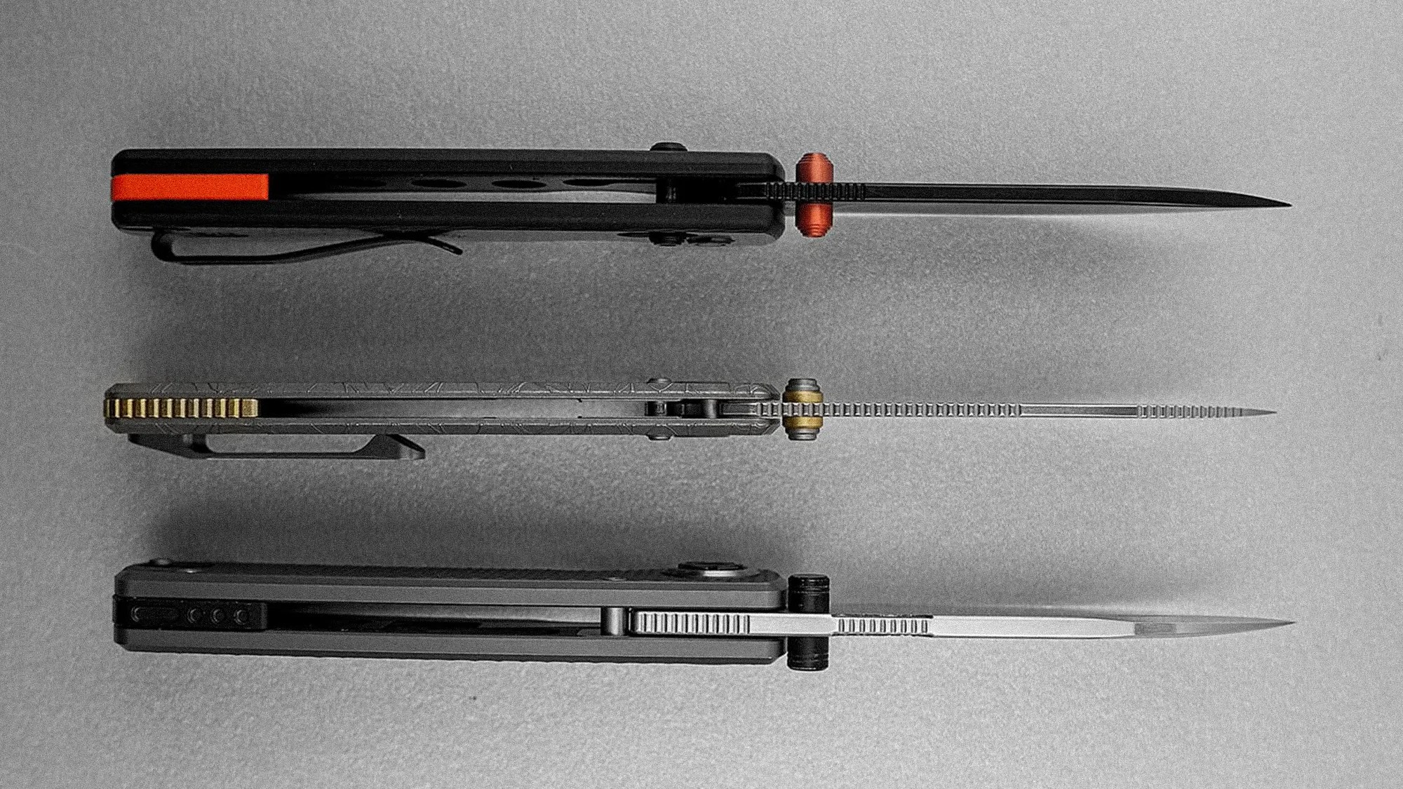 Three folding knives with blades partially open, shown from the top, featuring different handle designs and colors including black with orange, metallic with gold, and black with silver.