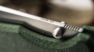 Close-up of a metallic object engraved with "BKR-10" resting on textured green fabric.