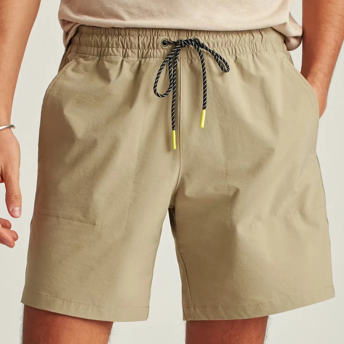 Khaki elastic waist shorts with black and white drawstring and front pockets worn by a person.