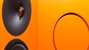 Close-up of an orange speaker cabinet featuring a black tweeter with a honeycomb grille and a woofer.