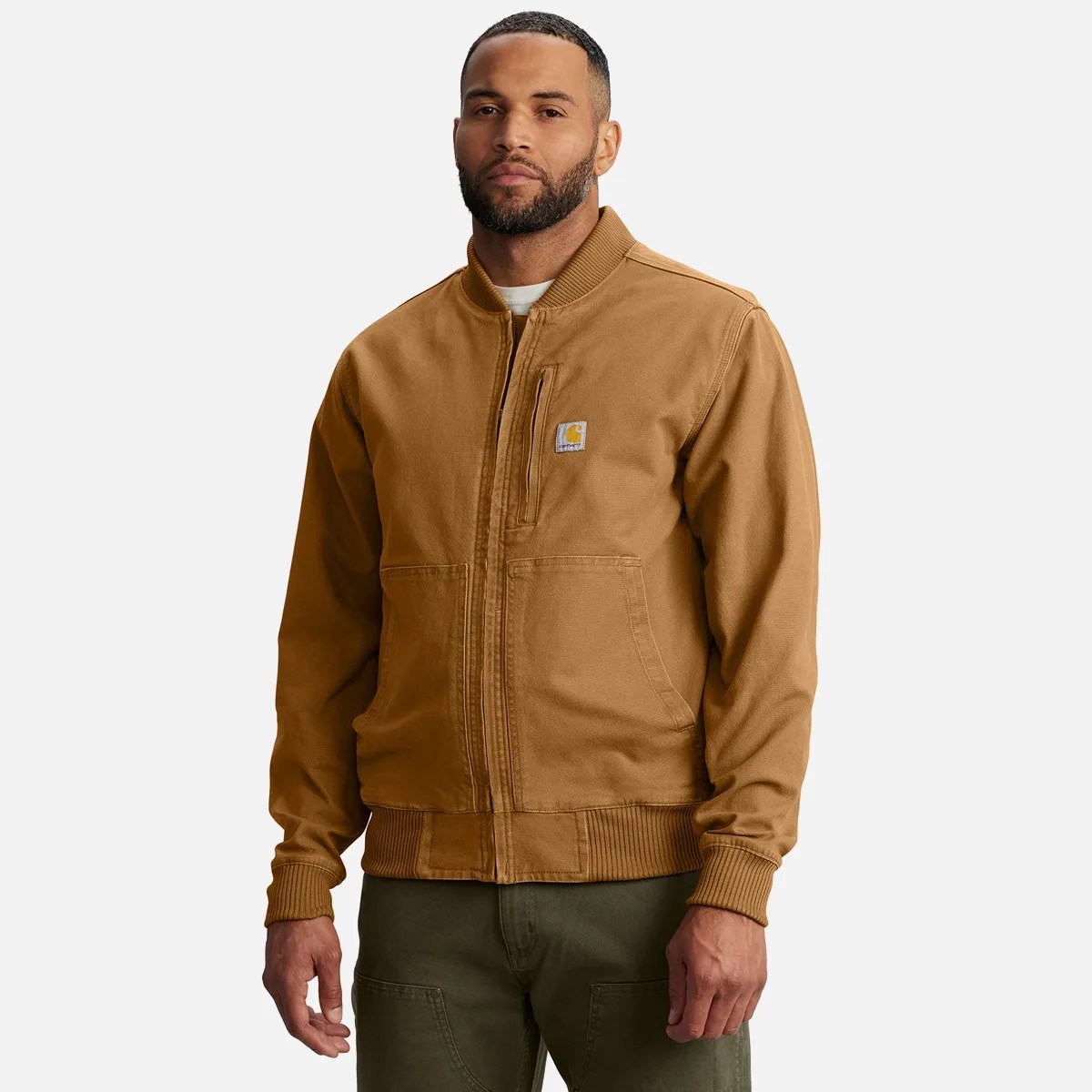 Brown Carhartt zip-up work jacket with ribbed cuffs and waistband worn by a person.