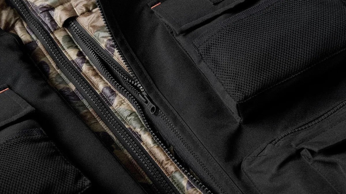 Close-up of a black jacket with a camouflage inner lining and visible zippers.