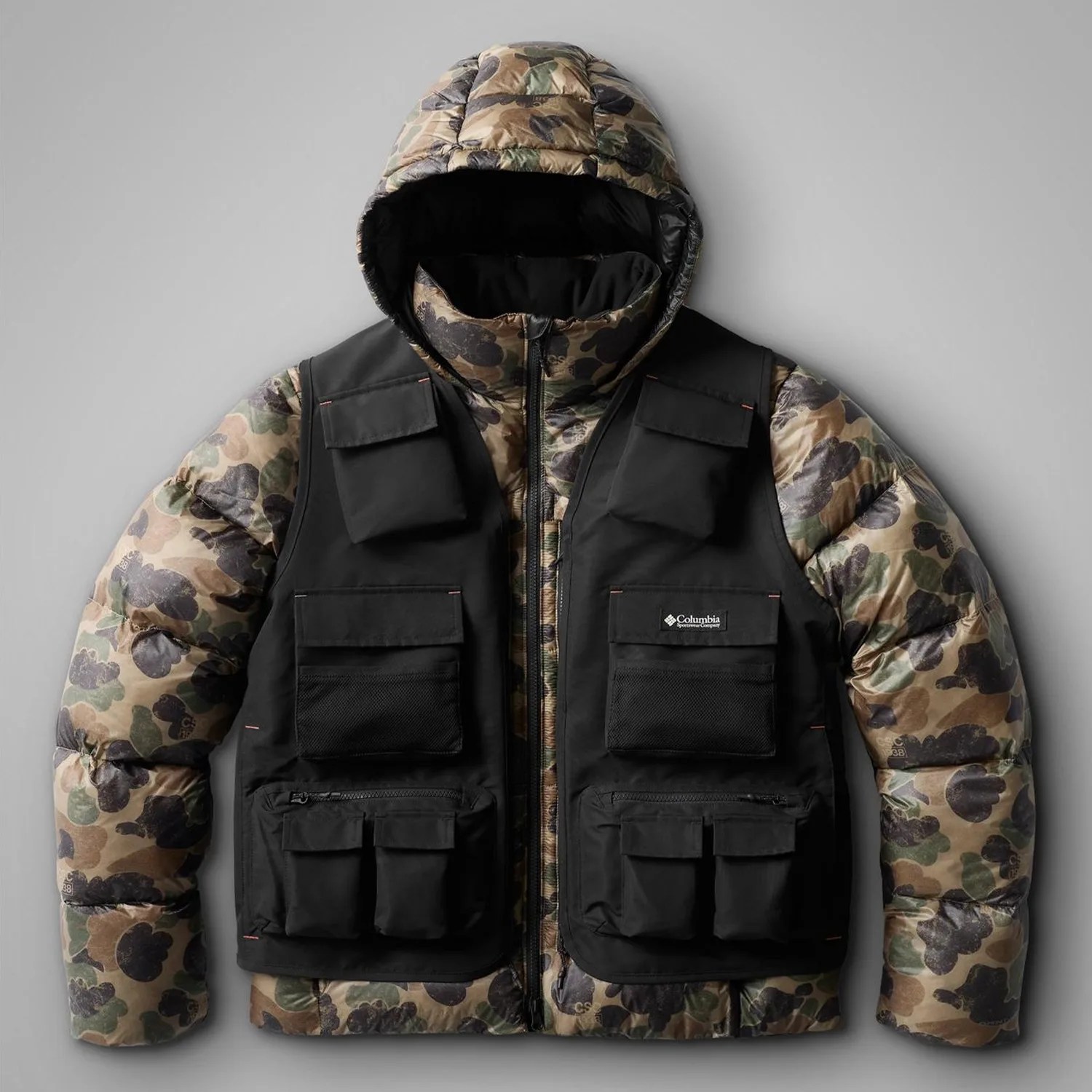 Camouflage puffer jacket with attached black utility vest featuring multiple pockets.