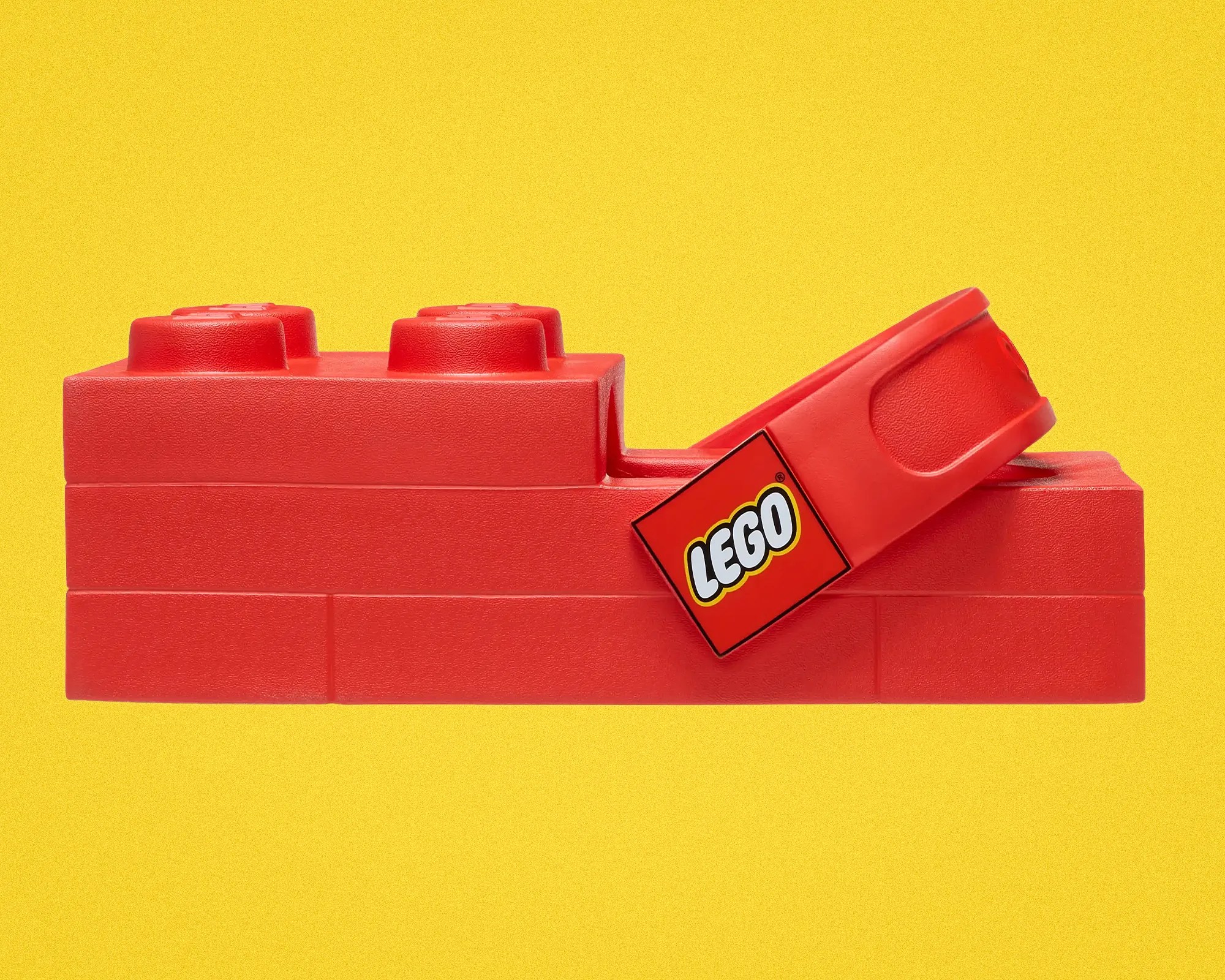 Red LEGO brick-shaped pencil sharpener with a yellow LEGO logo on a yellow background.