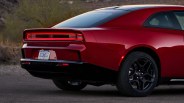 Rear side view of a red Dodge Daytona with black lower trim and black alloy wheels on a paved road.