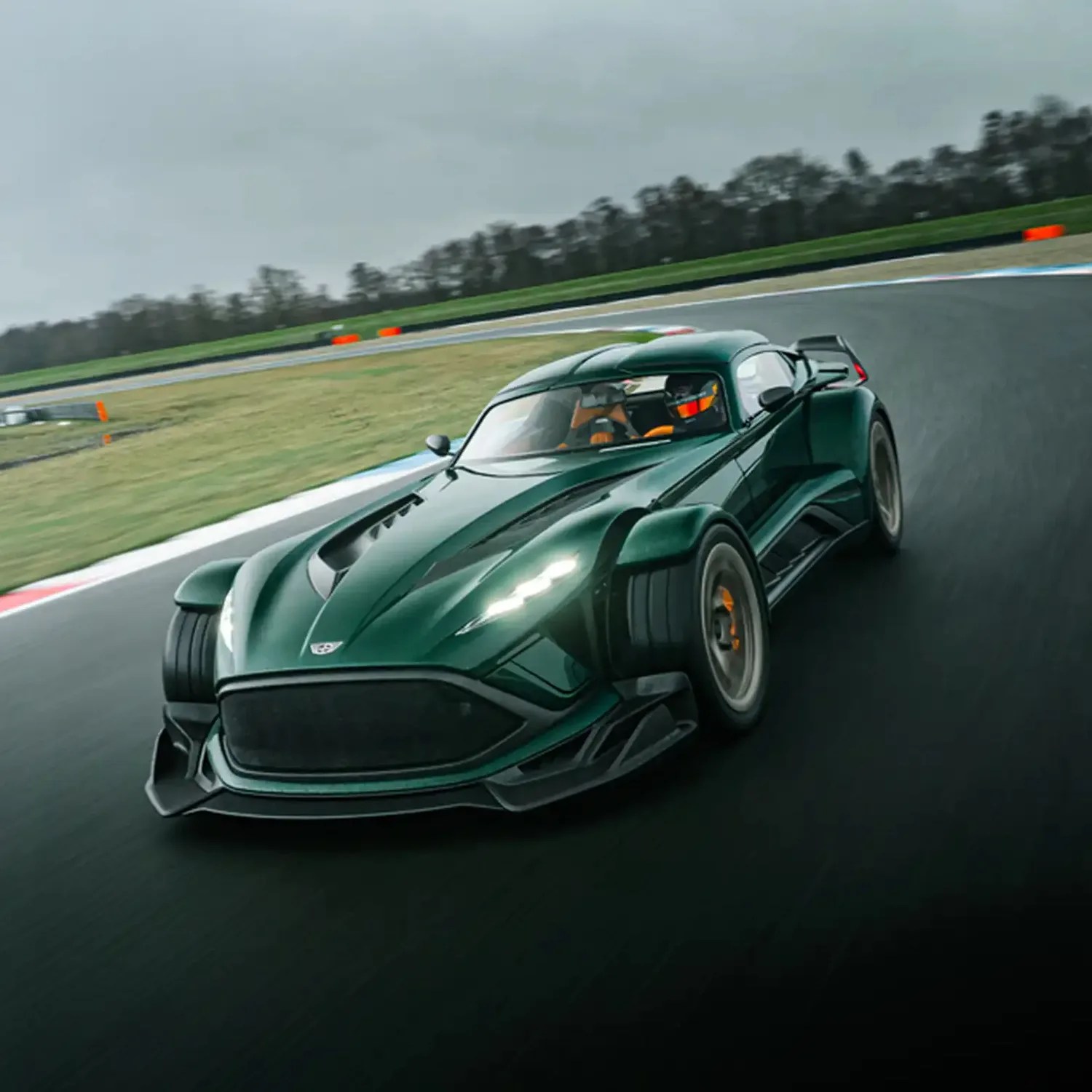 Dark green sports car with wide tires and aerodynamic design driving on a race track.