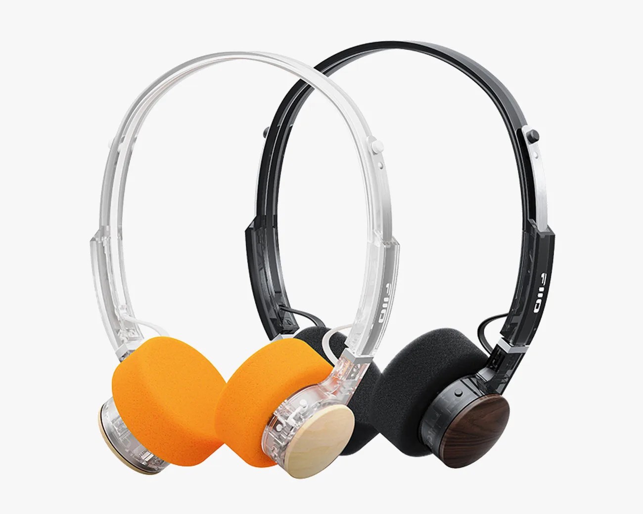 Two pairs of on-ear headphones, one with a clear frame and orange foam ear pads, the other with a black frame and black foam ear pads, both with wooden ear cup covers.