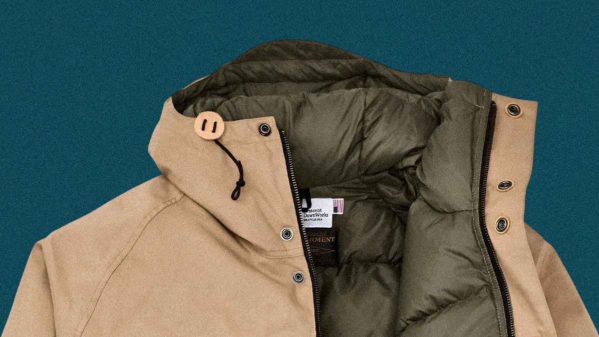Beige jacket with olive-green padded lining and black zipper on a teal background.