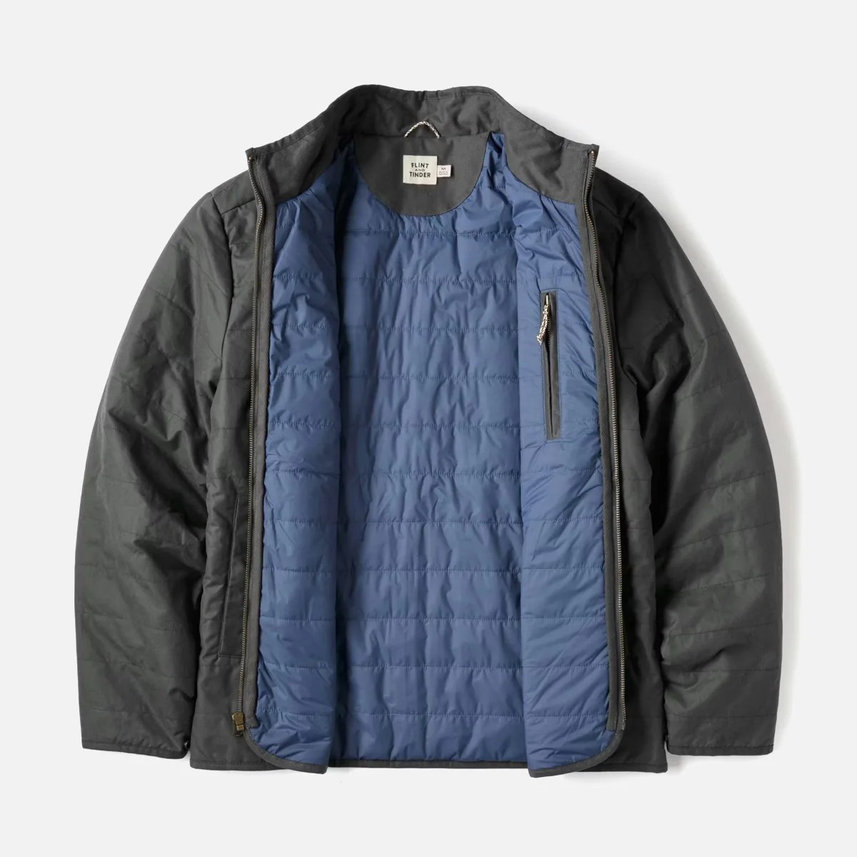 Dark gray quilted jacket with blue inner lining and zippered chest pocket opened flat.