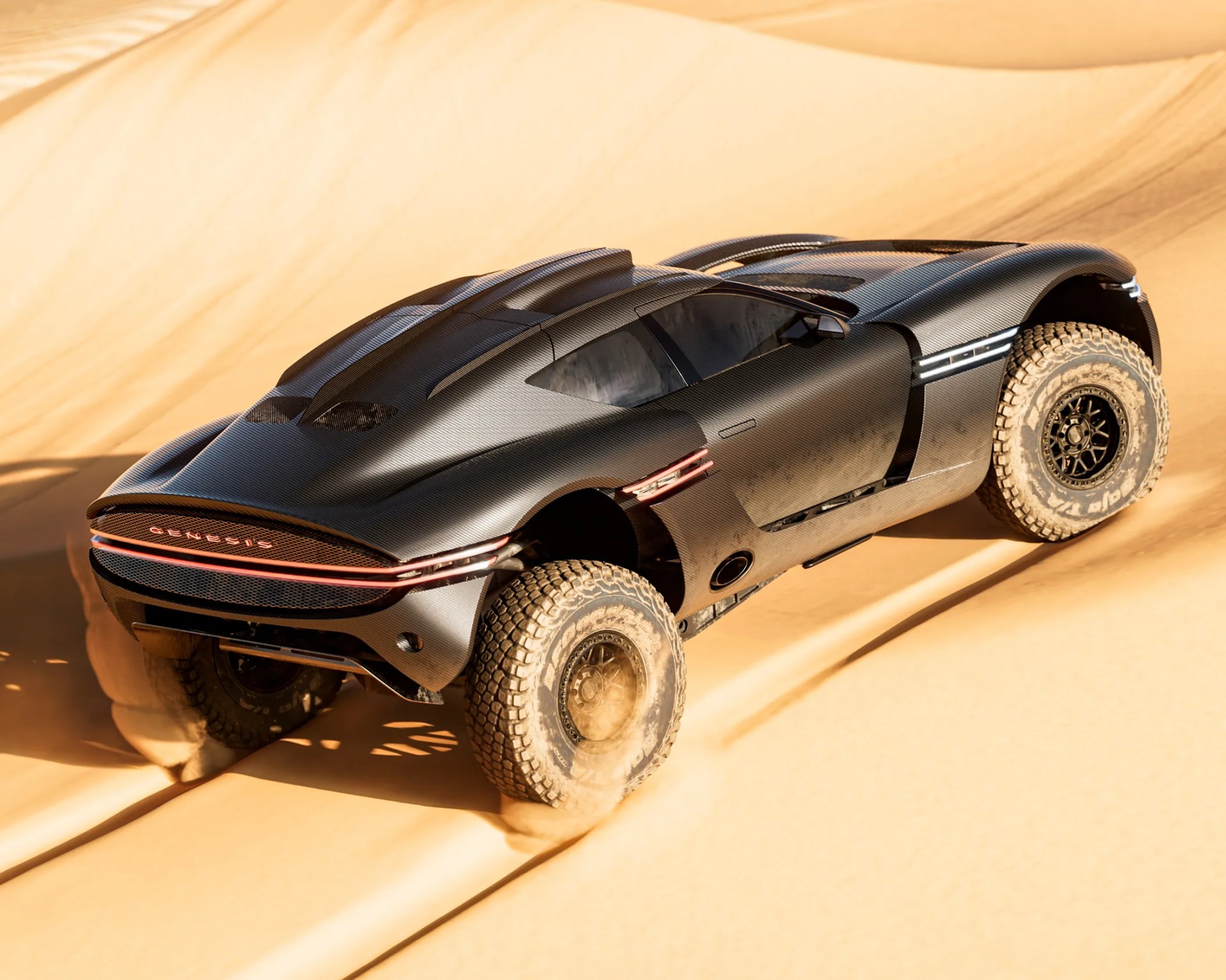 Matte black Genesis off-road vehicle with large knobby tires driving on sand dunes.