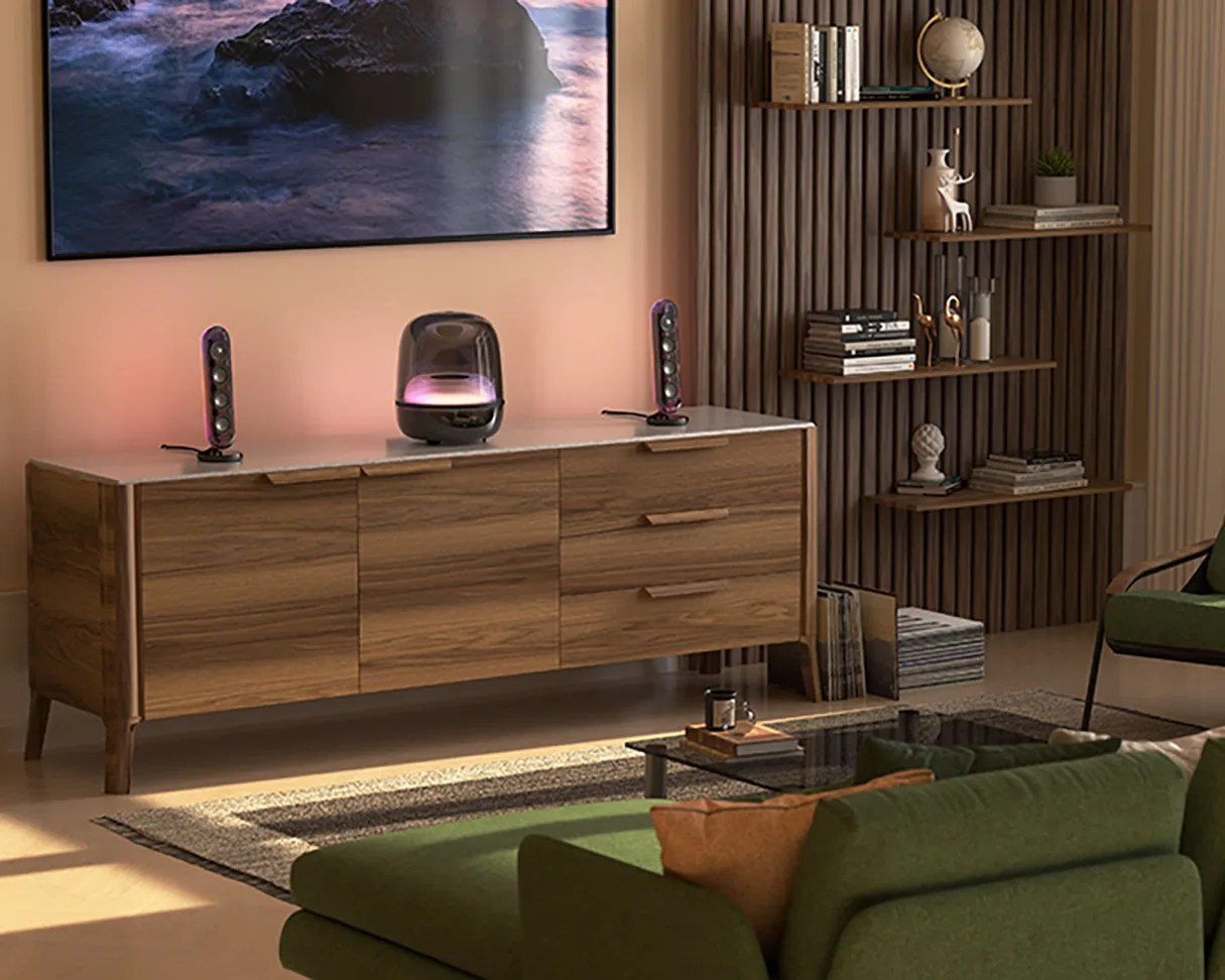 Wooden sideboard with marble top holding two vertical speakers and a black smart speaker with purple light in a living room.