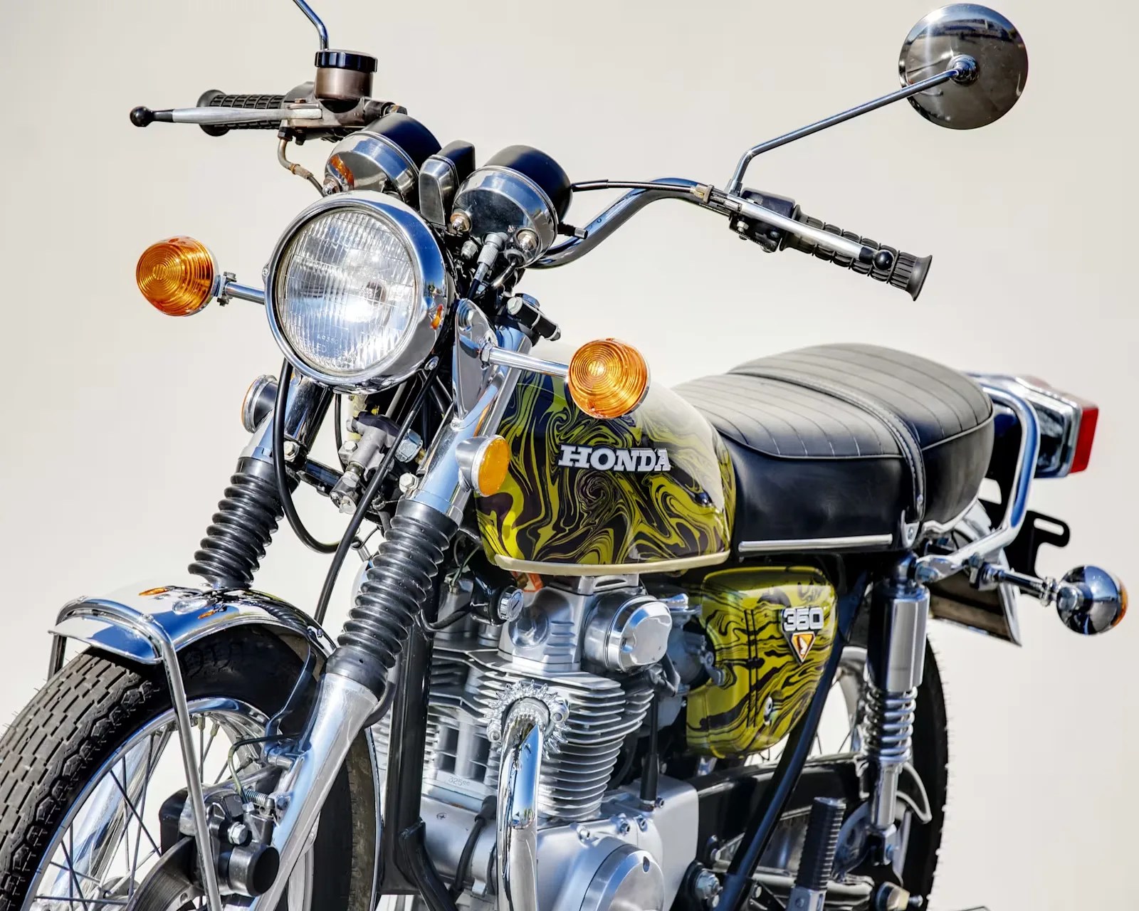 Vintage Honda 360 motorcycle with black and yellow marbled fuel tank and chrome details.