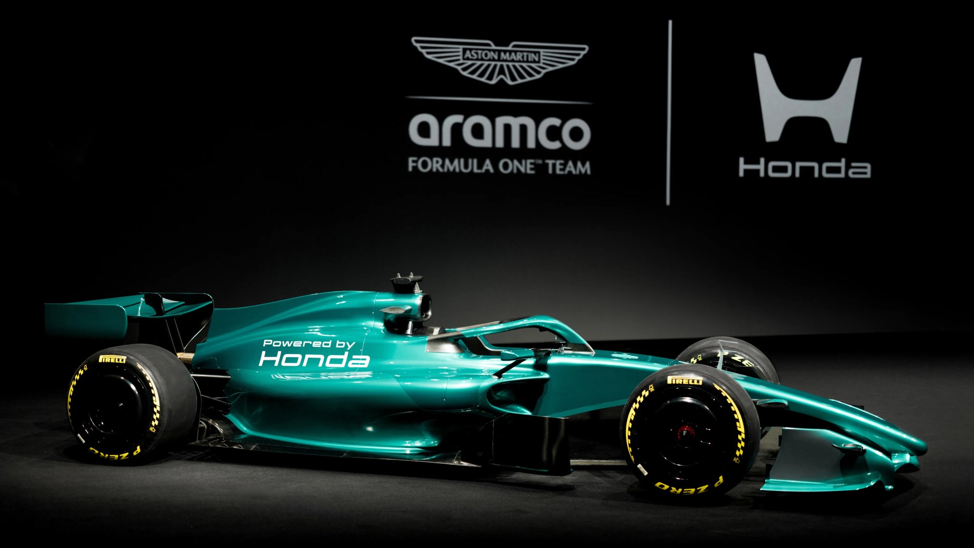 Teal Aston Martin Aramco Formula One car with "Powered by Honda" text on side, shown in profile on black background.
