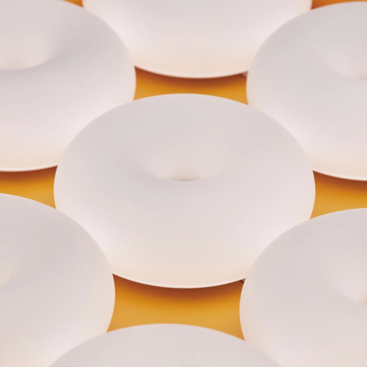 Seven white ceramic plates with a concave center arranged on an orange surface.